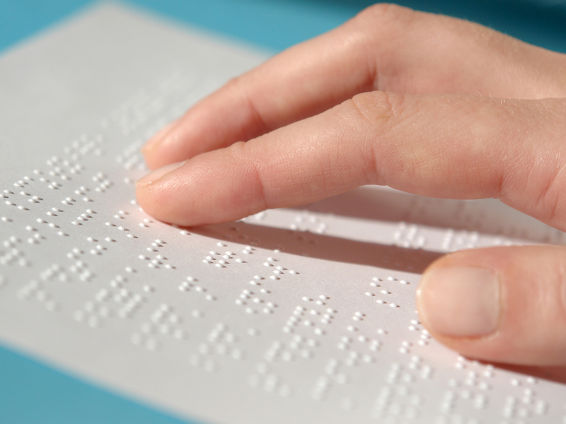 Fingers reading on a page of Braille